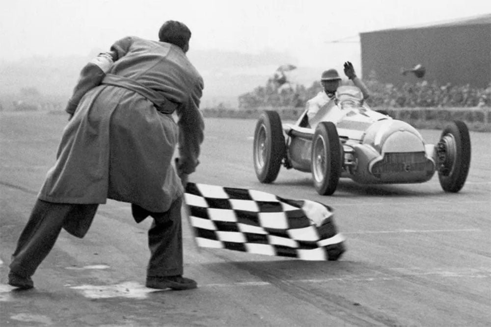 Auto de carrera de época recibiendo la bandera a cuadros